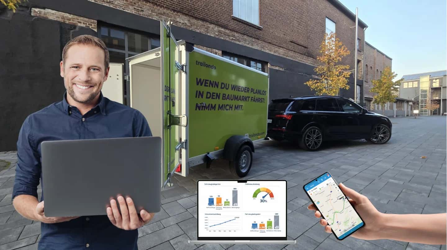 Smiling rental operator with a laptop in front of a green Trailondo box trailer, with the fleet dashboard and the Trailondo app on a smartphone in the foreground